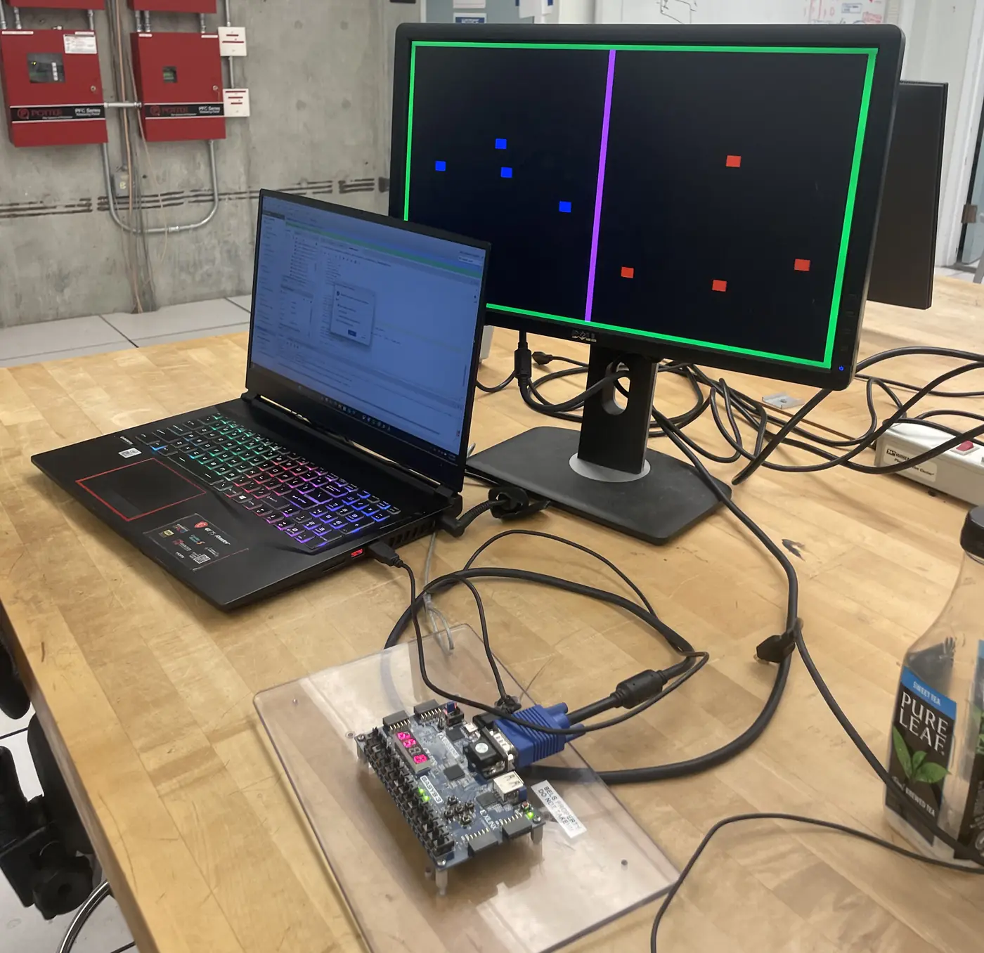 A win on the lab monitor: blues left, reds right, green border lit. Basys 3 in front, March 2025.